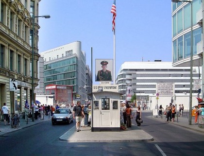 What to do in Berlin. Checkpoint Charlie as tourist attraction. The ersatz guard house viewed from what was the American sector. Beyond it is a mast with an image of a Soviet soldier. The reverse side shows an American soldier (June 2003). Photo: Wikipedia, Adrian Purser from London, UK. http://en.wikipedia.org/wiki/File:Checkpoint_Charlie_Berlin.jpg